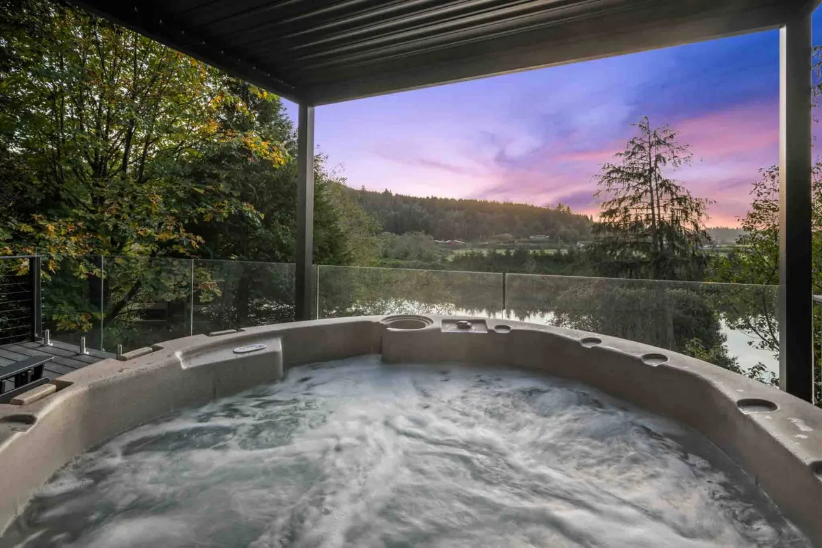 This exterior shot highlights the hot tub and deck area overlooking a stunning sunset sky, with vistas of the surrounding natural landscape. The view suggests moments of socializing or personal reflection while immersed in nature, emphasizing the connection between luxury and the outdoors.