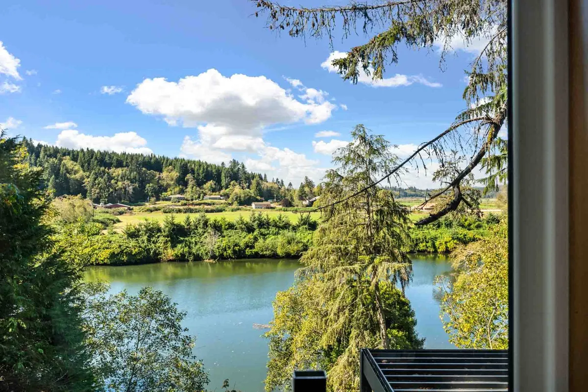 This sweeping view captures the Nehalem River winding through trees and hills beneath a broad sky, inviting thoughts of outdoor exploration, fishing, hiking, and wildlife watching. The image’s vastness expands the sense of place beyond the property itself, situating it within a scenic, natural landscape.