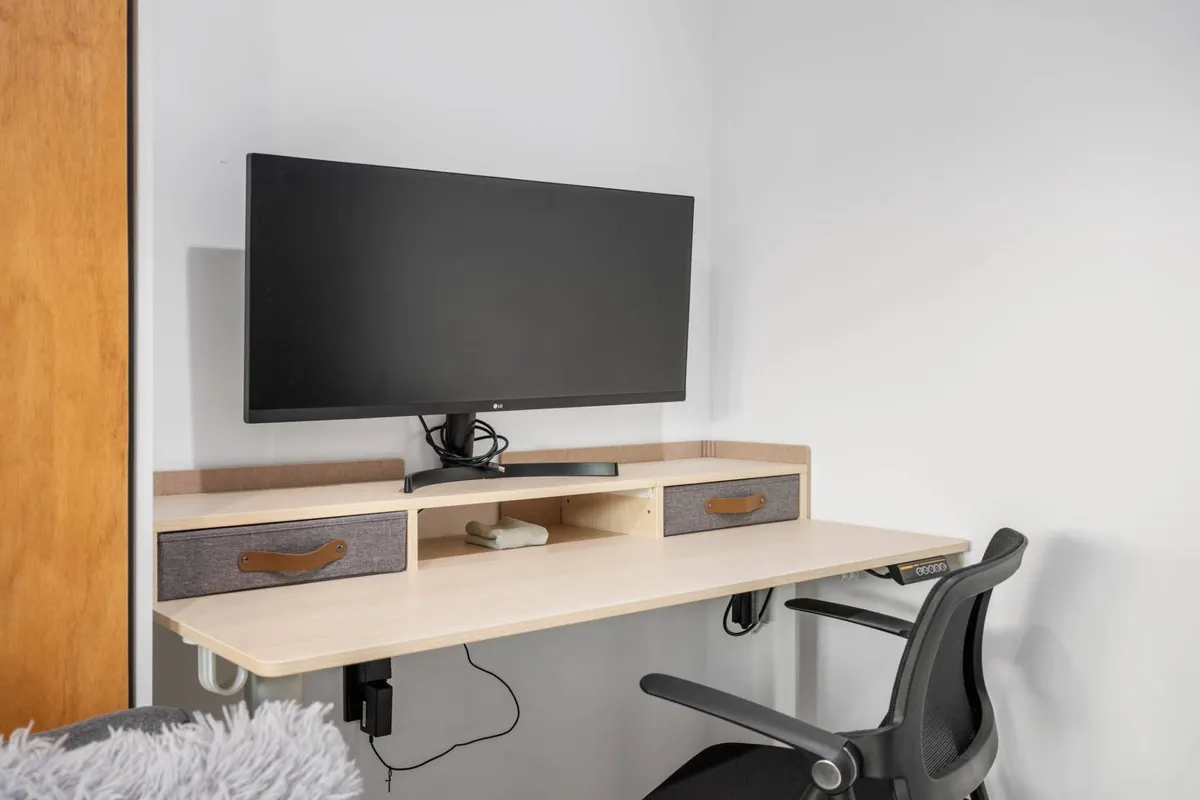A dedicated workspace featuring a modern computer monitor, a desk, and an ergonomic office chair. The space feels clean, uncluttered, and purpose-built for productivity, emphasizing a tech-forward environment ideal for remote work.